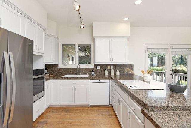 kitchen featuring stainless steel appliances, white cabinetry, sink, and backsplash