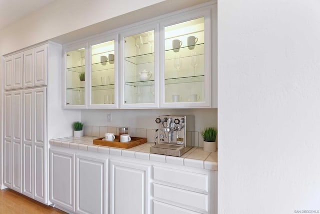 bar featuring white cabinetry and tile countertops