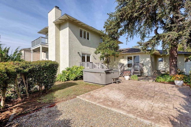 rear view of house with a balcony, a hot tub, and a patio area