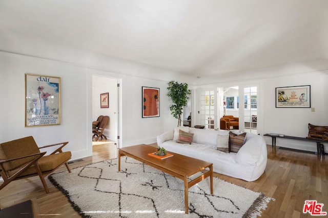 living room with french doors, wood-type flooring, and vaulted ceiling