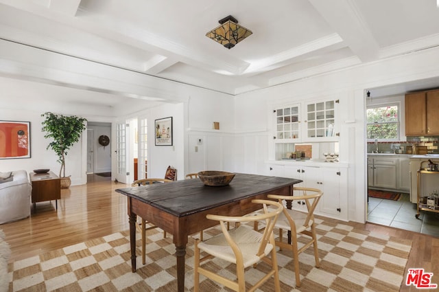 dining room featuring coffered ceiling, ornamental molding, light hardwood / wood-style floors, and beamed ceiling