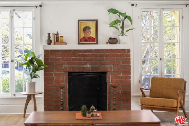 living room featuring wood-type flooring, a brick fireplace, and plenty of natural light