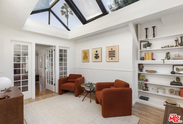 living area featuring a skylight, french doors, and light wood-type flooring