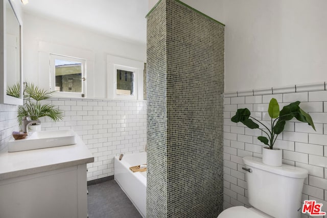 bathroom with a bath, vanity, tile walls, and toilet