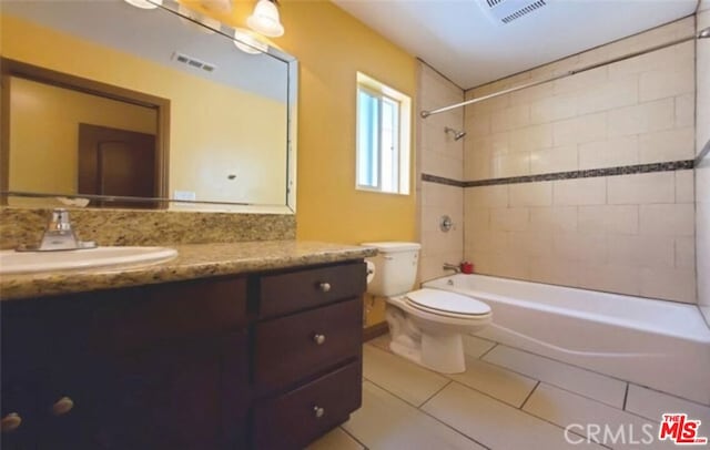 full bathroom with tile patterned flooring, vanity, tiled shower / bath combo, and toilet