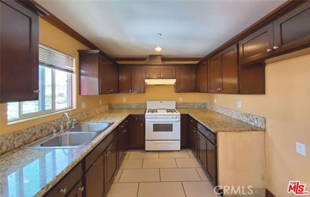 kitchen with light tile patterned flooring, sink, gas range gas stove, light stone countertops, and dark brown cabinets