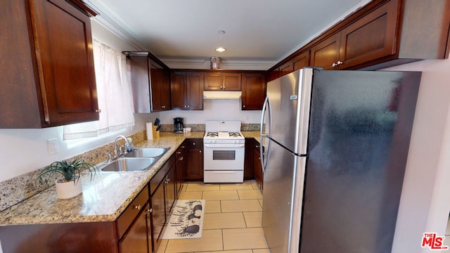 kitchen featuring sink, white range with gas stovetop, light stone counters, light tile patterned floors, and stainless steel fridge