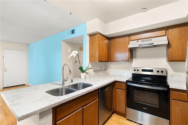 kitchen with stainless steel appliances, light stone countertops, sink, and kitchen peninsula