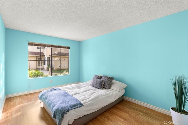 bedroom with light hardwood / wood-style flooring and a textured ceiling