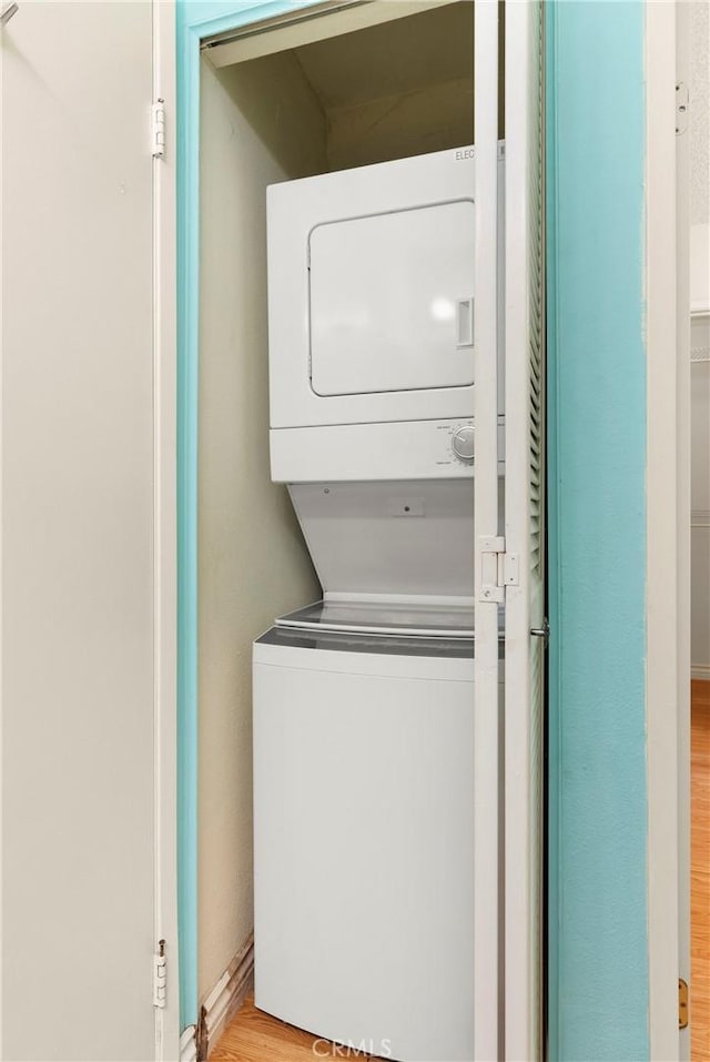 laundry area with light wood-type flooring and stacked washing maching and dryer