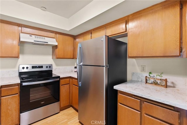 kitchen featuring light stone counters, light wood-type flooring, and appliances with stainless steel finishes