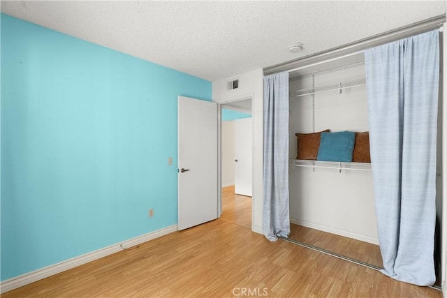 unfurnished bedroom featuring a closet, a textured ceiling, and light wood-type flooring