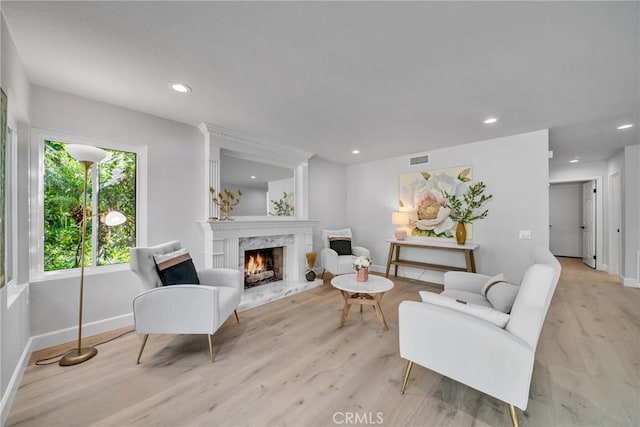 living room featuring a high end fireplace and light hardwood / wood-style floors