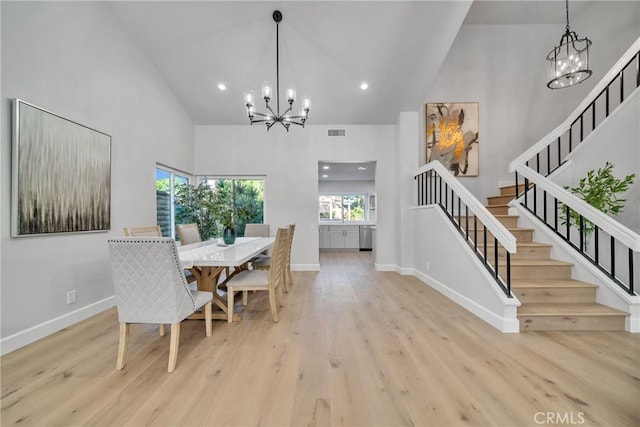 dining space featuring high vaulted ceiling, an inviting chandelier, and light hardwood / wood-style floors