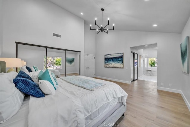 bedroom with high vaulted ceiling, an inviting chandelier, and light hardwood / wood-style floors