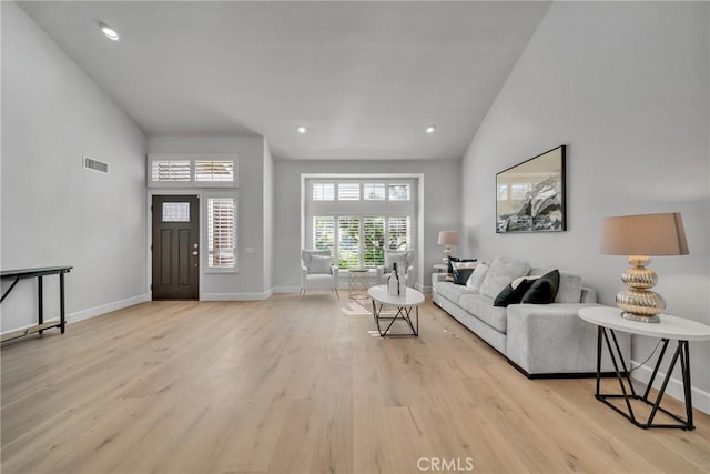 living room with high vaulted ceiling and light hardwood / wood-style flooring