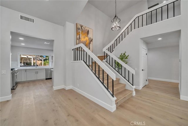 stairs featuring hardwood / wood-style flooring, an inviting chandelier, and a high ceiling