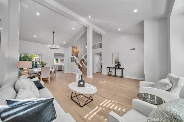 living room featuring beamed ceiling, high vaulted ceiling, an inviting chandelier, and light wood-type flooring