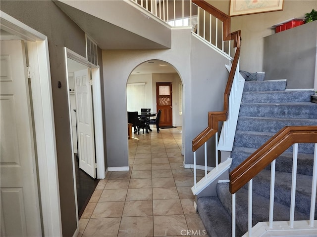 stairway featuring tile patterned flooring and a towering ceiling