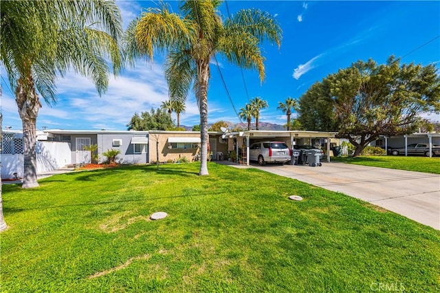 ranch-style house featuring stucco siding, driveway, fence, a front yard, and an attached carport