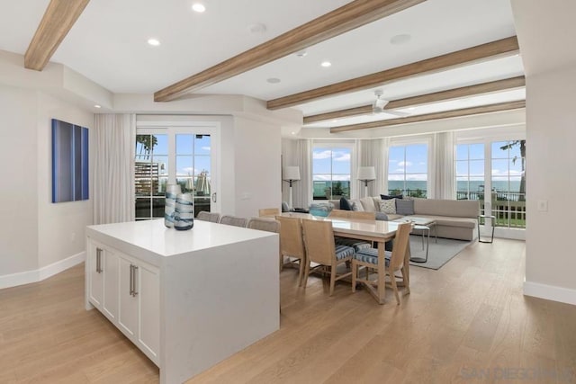 kitchen with white cabinetry, beam ceiling, a center island, and light hardwood / wood-style floors