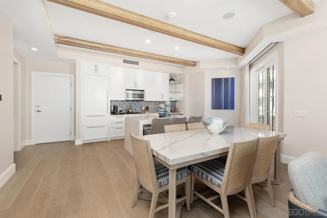 dining space with beam ceiling and light hardwood / wood-style flooring