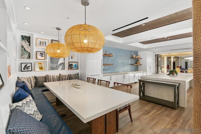 dining room with breakfast area, a tray ceiling, and light wood-type flooring