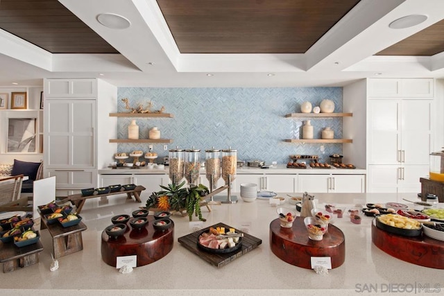 kitchen featuring wood ceiling, backsplash, a raised ceiling, and white cabinets