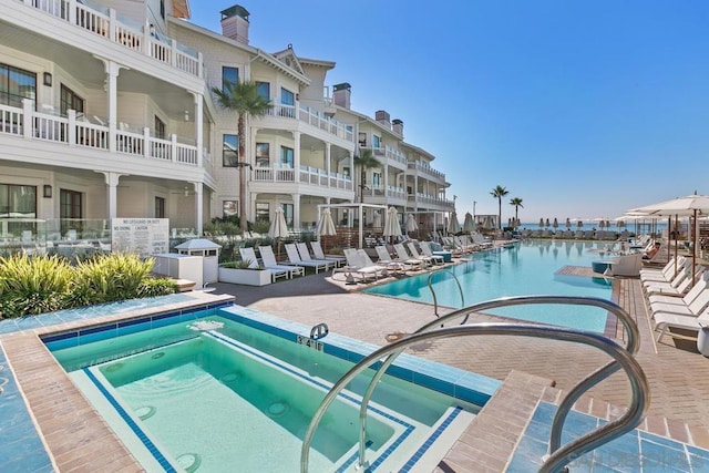 view of pool with a patio area, a community hot tub, and a water view