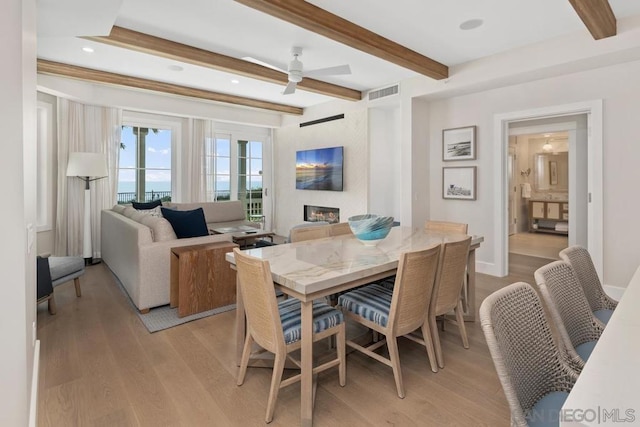 dining area with ceiling fan, beam ceiling, and light hardwood / wood-style flooring