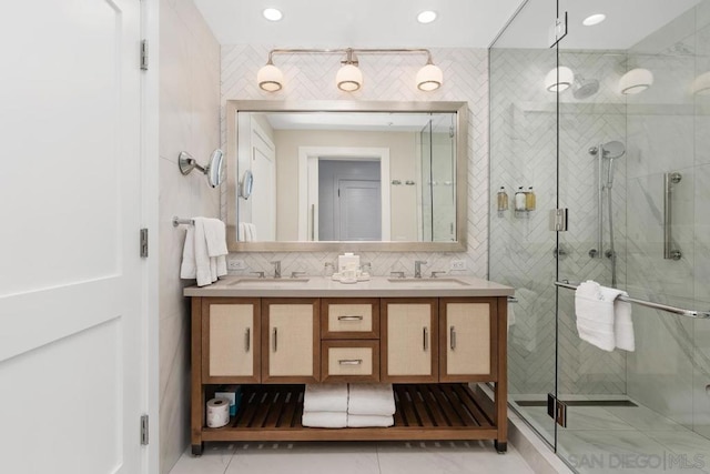 bathroom featuring tile walls, backsplash, vanity, a shower with shower door, and tile patterned floors