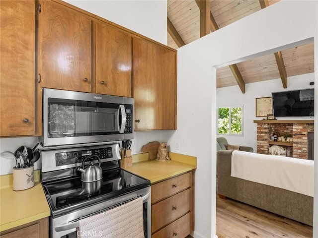 1153 Silvertip Ln, Fish Camp, CA 93623 - kitchen featuring light hardwood / wood-style flooring, appliances with stainless steel finishes, a fireplace, lofted ceiling with beams, and wooden ceiling