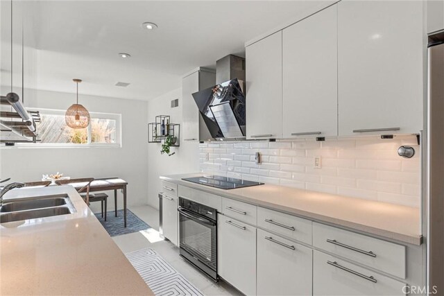 kitchen featuring sink, black appliances, hanging light fixtures, decorative backsplash, and white cabinets