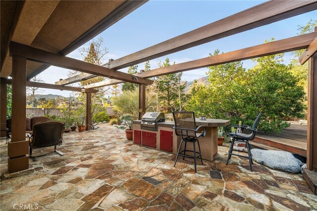 view of patio featuring a bar, an outdoor kitchen, grilling area, and a pergola