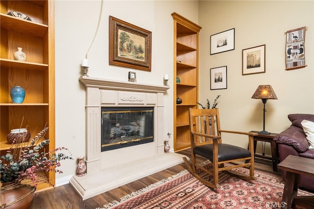 sitting room featuring a high end fireplace, wood-type flooring, and built in features