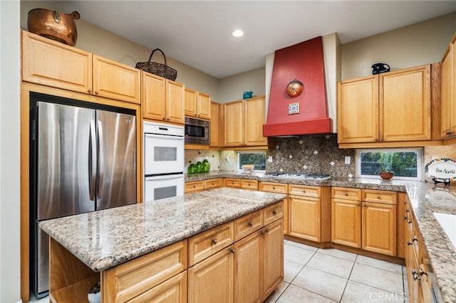 kitchen featuring premium range hood, appliances with stainless steel finishes, tasteful backsplash, a center island, and light tile patterned floors