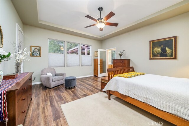 bedroom featuring a tray ceiling, dark hardwood / wood-style floors, and ceiling fan