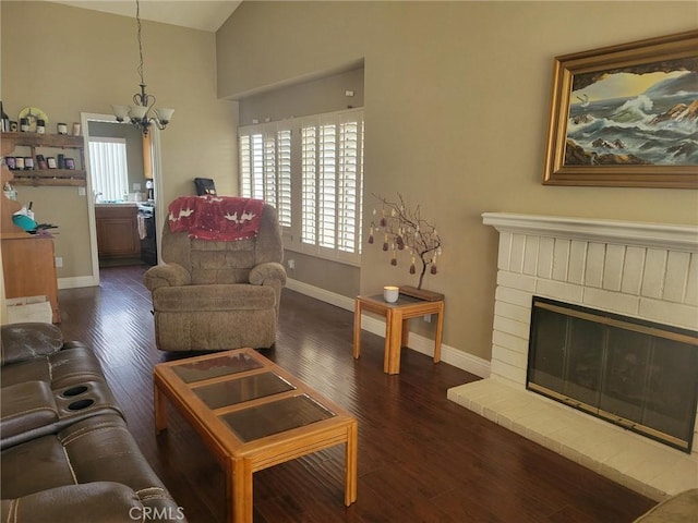 living room with vaulted ceiling, an inviting chandelier, a fireplace, and dark hardwood / wood-style flooring