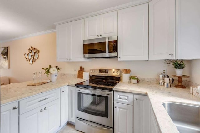 kitchen with white cabinetry, stainless steel appliances, crown molding, and light stone counters