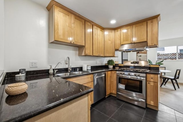 kitchen with stainless steel appliances, kitchen peninsula, sink, and dark stone countertops