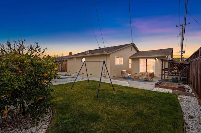 back house at dusk featuring a yard, an outdoor hangout area, and a patio area