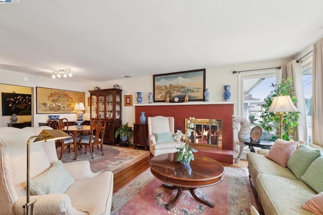 living room with a brick fireplace and wood-type flooring