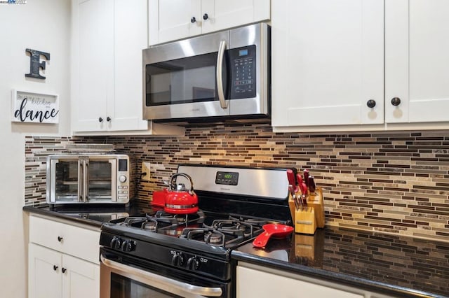 kitchen with tasteful backsplash, stainless steel appliances, dark stone counters, and white cabinets