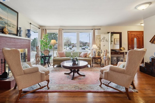 living room with a brick fireplace and wood-type flooring