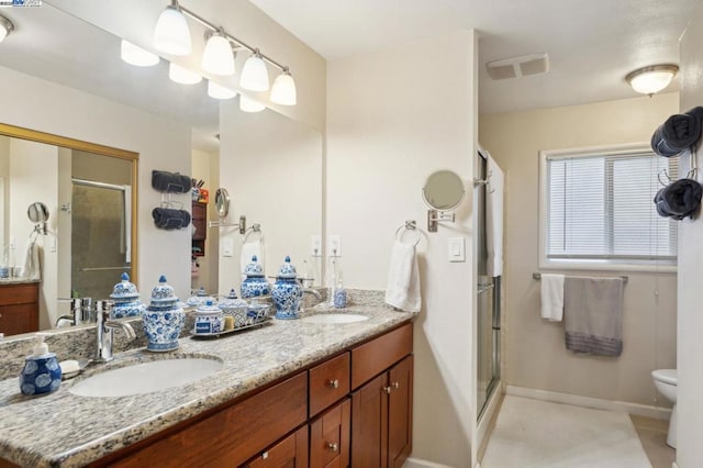 bathroom with a shower with door, vanity, and toilet