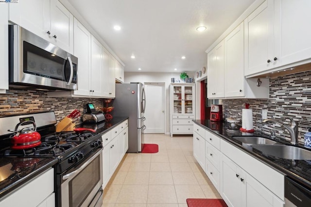 kitchen featuring sink, light tile patterned floors, appliances with stainless steel finishes, decorative backsplash, and white cabinets