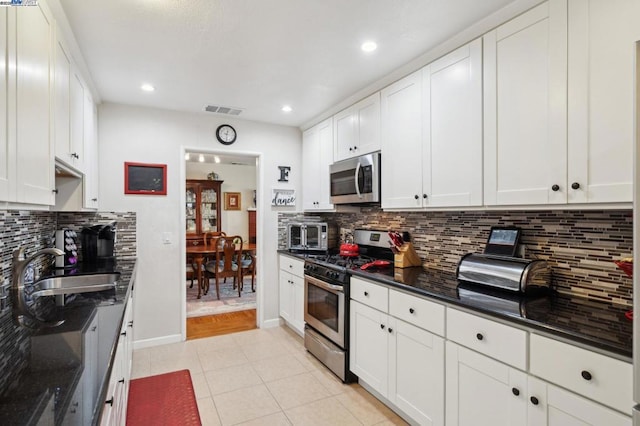 kitchen featuring appliances with stainless steel finishes, white cabinetry, sink, decorative backsplash, and light tile patterned floors