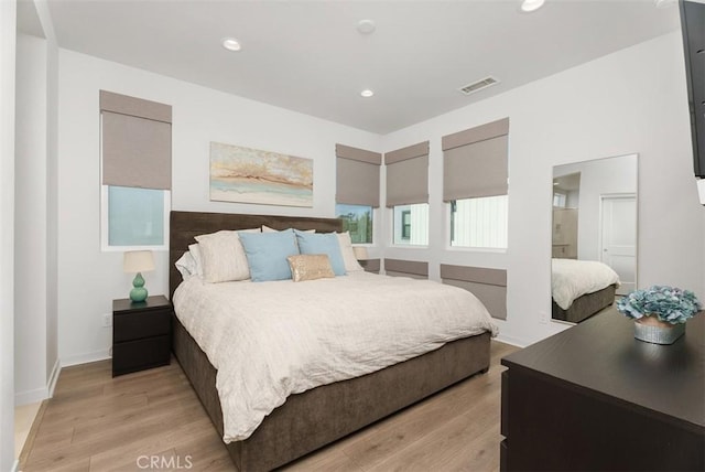 bedroom with ensuite bath and light wood-type flooring