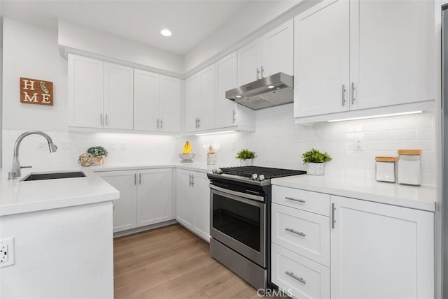 kitchen featuring white cabinetry, sink, backsplash, stainless steel range with gas stovetop, and light wood-type flooring