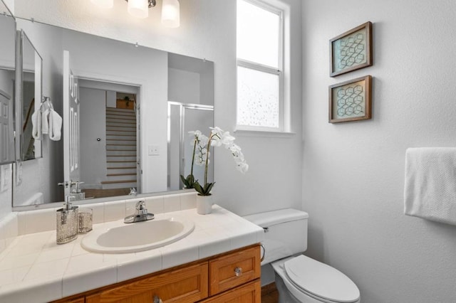 bathroom featuring a shower with door, vanity, and toilet